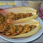 A plate of golden-brown vazhaipoo vada, crispy on the outside and soft inside, served with fresh curry leaves and a side of coconut chutney.