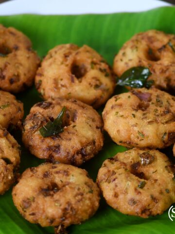 Golden brown, crispy Poha Vada served on a plate, garnished with fresh coriander and accompanied by green chutney. The vadas have a crunchy exterior with a soft, spiced flattened rice (poha) filling.