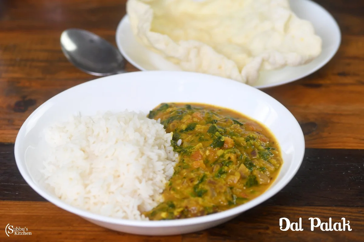 A bowl of creamy Dal Palak, made with lentils and spinach, garnished with tempering of mustard seeds, cumin, and red chilies, served hot with rice or roti.
